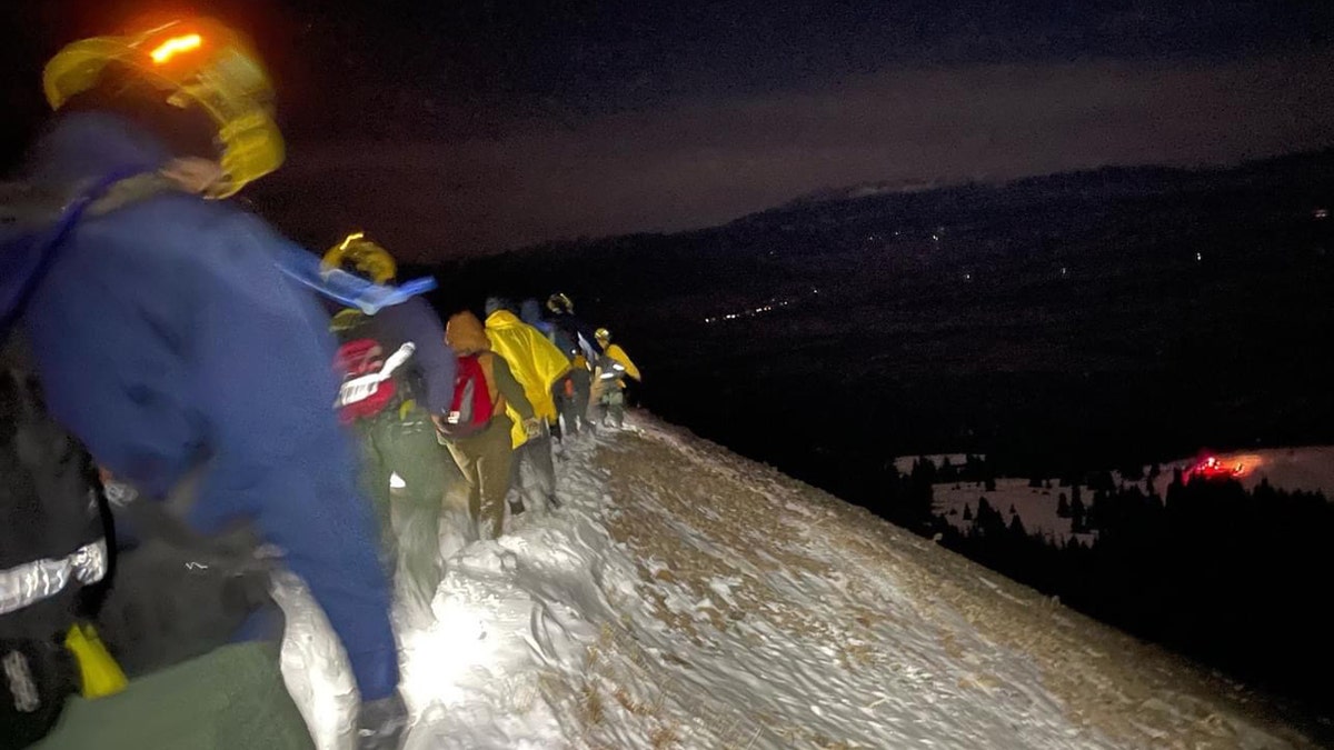 rescue workers walking along a mountain in Colorado with a family they rescued